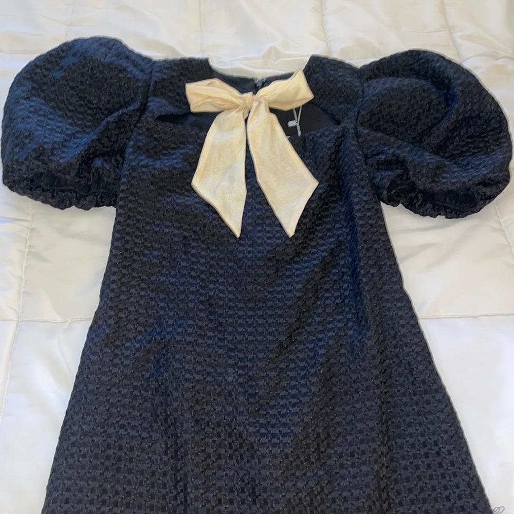 Black dress with puff sleeves with a cream bow on the front